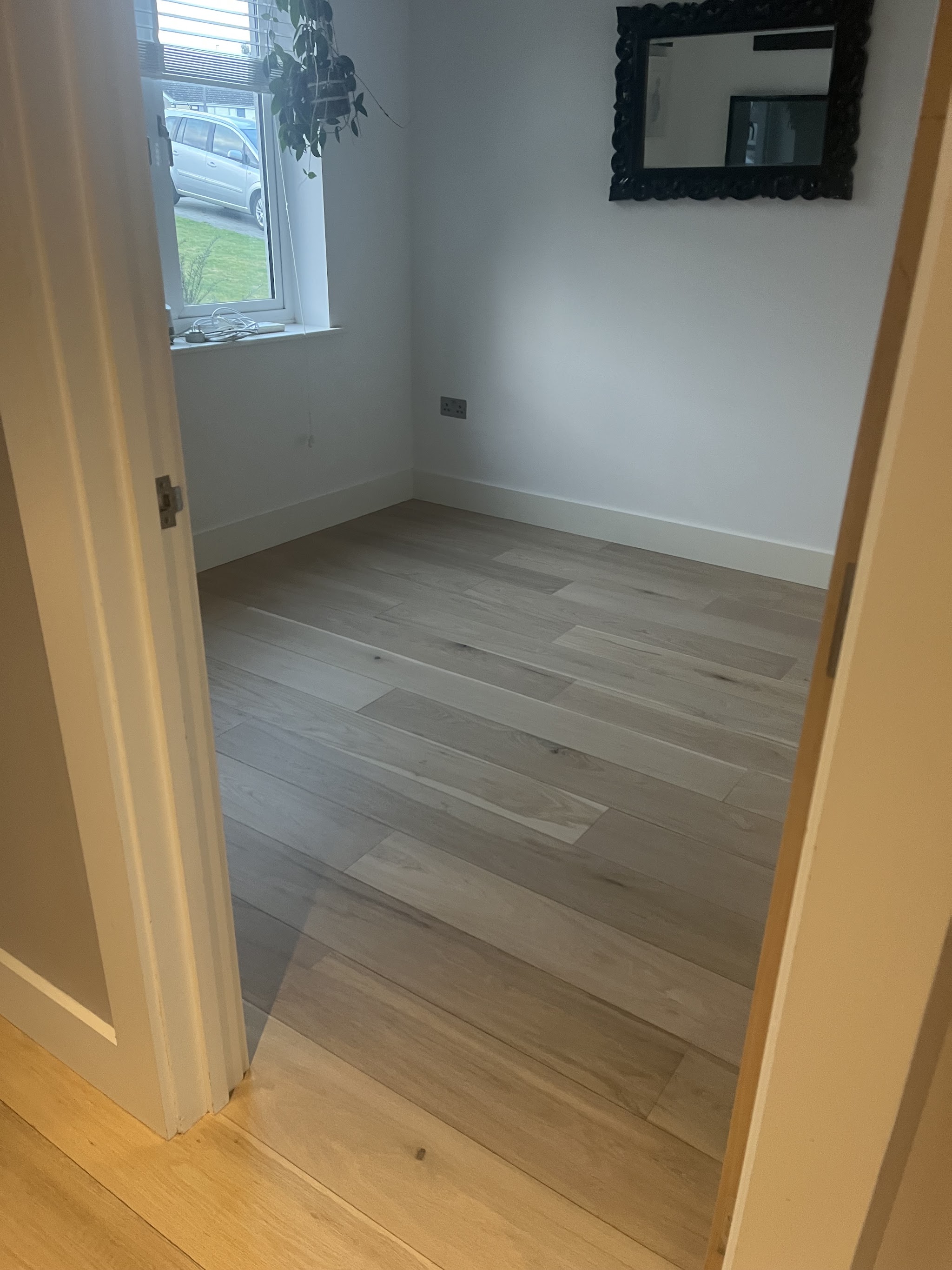 A finished engineered oak plank floor in a bedroom, seen through the doorway, photographed by the customer